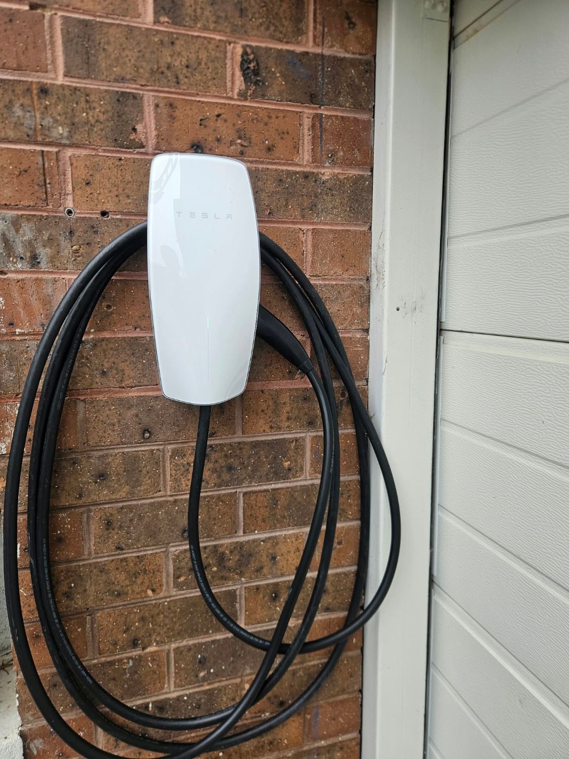 Tesla EV charger installed on a brick garage wall, West Suburbs